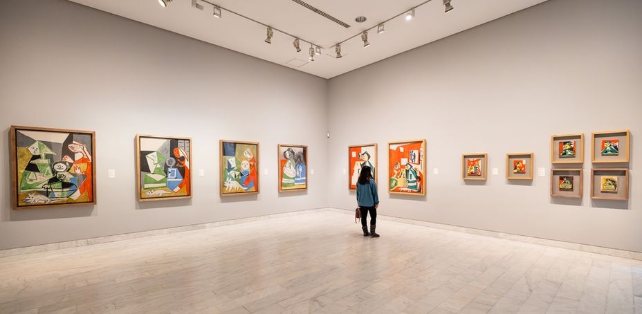 Barcelona, Spain - January 2023: A woman admiring colorful paintings in the Picasso Museum gallery, surrounded by abstract and modern artworks.