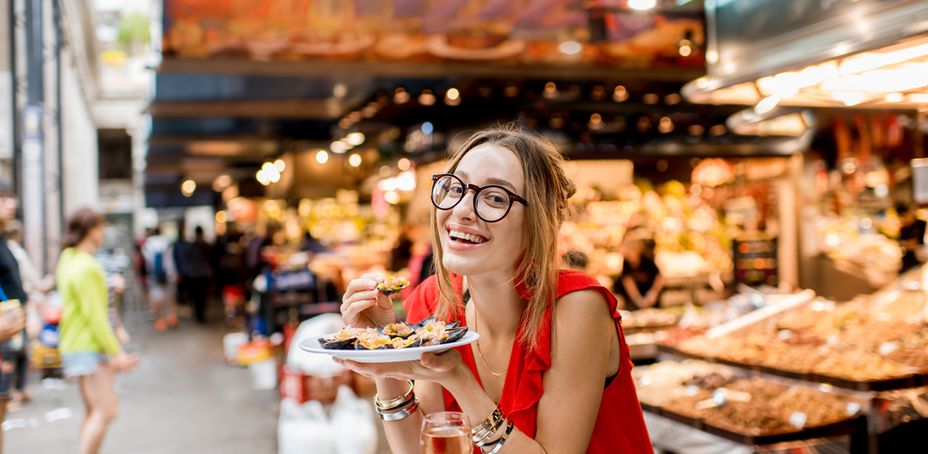 Young woman in red dress having lunch with mussels and rose wine sitting at the food market