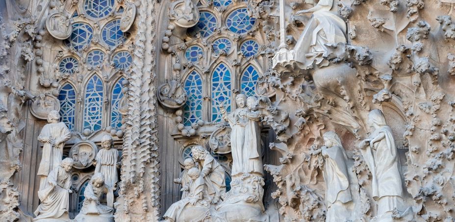 Detail of Sagrada Familia facade featuring intricate stone carvings and stained glass windows.