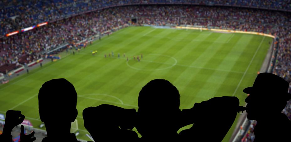 Silhouettes of spectators watching a football match in the stadium.