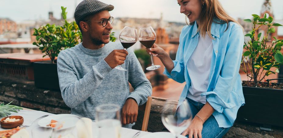 A happy couple dressed in casual clothes eating on the terrace of a restaurant with a beautiful view in Barcelona