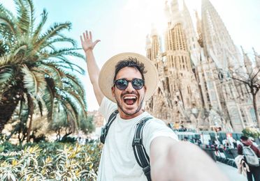 Smiling tourist taking a selfie near Sagrada Familia in Barcelona