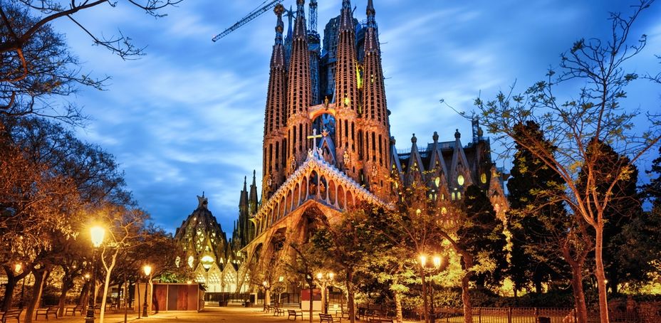 Vista nocturna de la icónica Sagrada Familia de Barcelona, iluminada con luces cálidas.