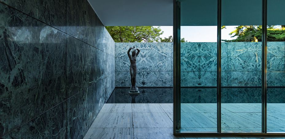 Interior view of the renowned Barcelona Pavilion featuring marble walls, glass panels, and a sculpture.