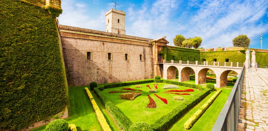 View of the gardens at Montjuic Castle with a stone wall and greenery